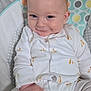 baby, infant, smiling, onesie, giraffe_pattern, baby_seat, cozy, cute, hand, face, blue_eyes, soft_fabric, clothing, child, portrait, indoor, cute_expression, sitting, light_skin, blond_hair