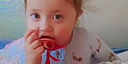 Victoria is registered to the contest to win money with this photo: toddler, child, pacifier, ribbon, pajamas, blanket, bed, indoor, cute, face, hair_bow, expression, young, person, sleepwear, comfort, soft_light, curious, hands, cozy
