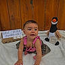 baby, child, crawling, pink_overalls, camo_skirt, white_blanket, wooden_fence, egg_carton, eggs, sign, plush_duck, milestone, six_months, half_dozen, cute, smiling, indoors, portrait, celebration, infant