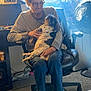 Princess is registered to the contest to win money with this photo: carpet, casual_clothing, chair, computer_monitor, decor, dog, elderly_person, fan, glasses, holding, home, indoor, jeans, long_sleeve_shirt, office_chair, pet, portrait, relaxing, sitting, window