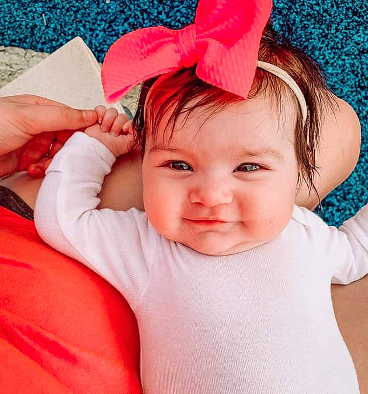 Bayleigh is registered to the contest to win money with this photo: baby_toddler_clothing, dress, ear, eyebrow, eyelash, finger, gesture, hair, hand, happy, head, headgear, lip, neck, person, pink, red, skin, sleeve, smile