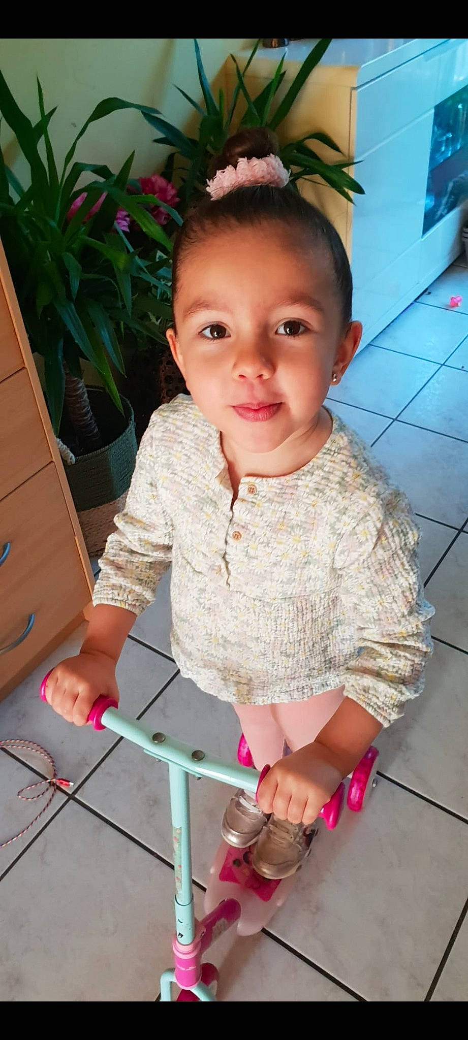 Layna participe au concours pour gagner de l'argent avec cette photo : baby_toddler_clothing, cheek, child, flooring, flowerpot, fun, happy, headband, headpiece, houseplant, magenta, pattern, person, pink, plant, sitting, skin, sleeve, smile, t_shirt