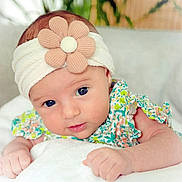Julia participe au concours pour gagner de l'argent avec cette photo : baby, infant, headband, flower, blanket, cute, portrait, face, skin, child, young, clothing, patterned, floral, soft, indoors, closeup, hands, expression, lying_down