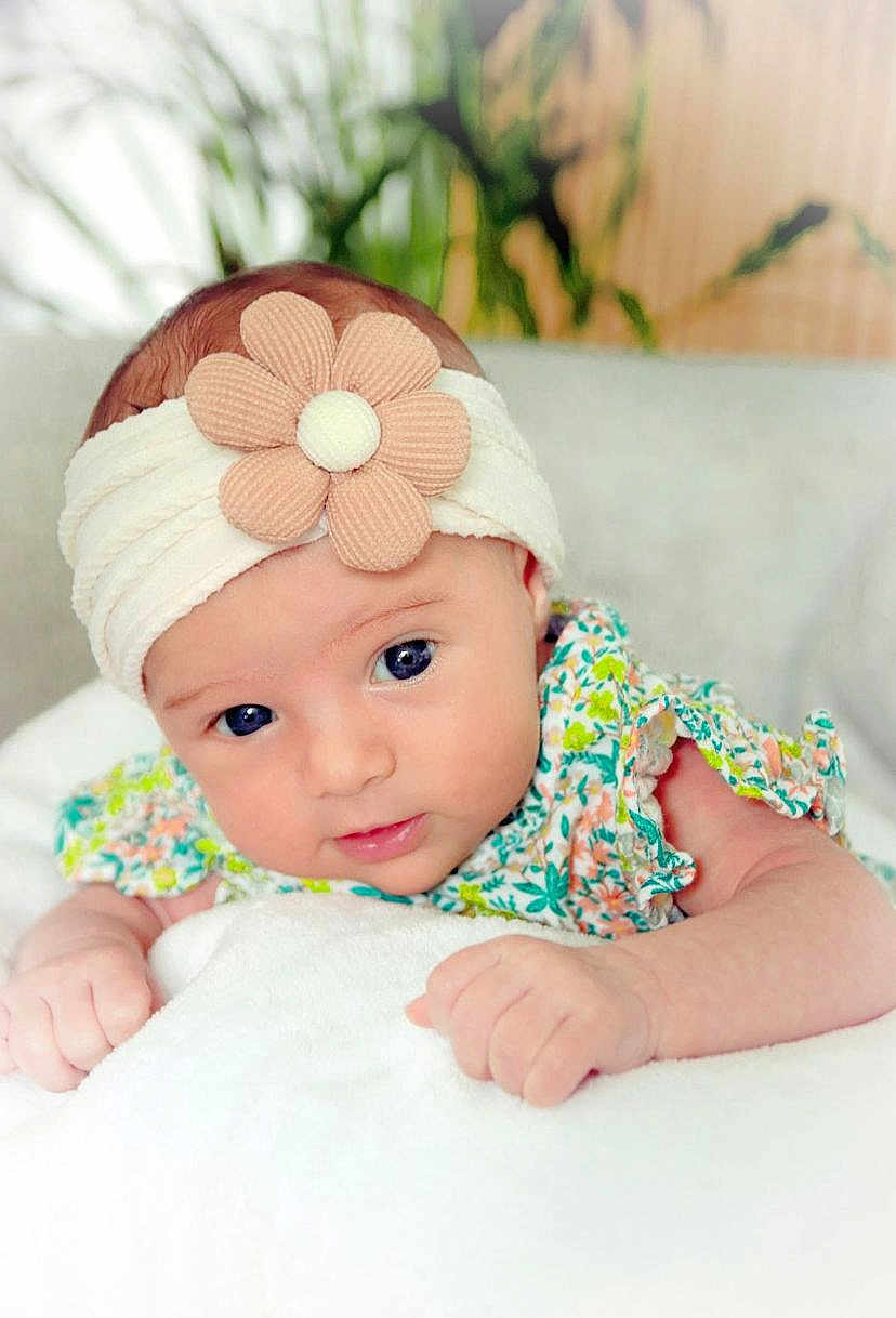 Julia participe au concours pour gagner de l'argent avec cette photo : baby, infant, headband, flower, blanket, cute, portrait, face, skin, child, young, clothing, patterned, floral, soft, indoors, closeup, hands, expression, lying_down