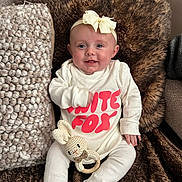 Mabel joined the competition — help win amazing prizes! baby, blanket, bow, bunny_toy, child, couch, cozy, cute, furry_blanket, happy, headband, indoor, infant, knitted_toy, portrait, sitting, smiling, soft_texture, text_on_clothing, white_clothing