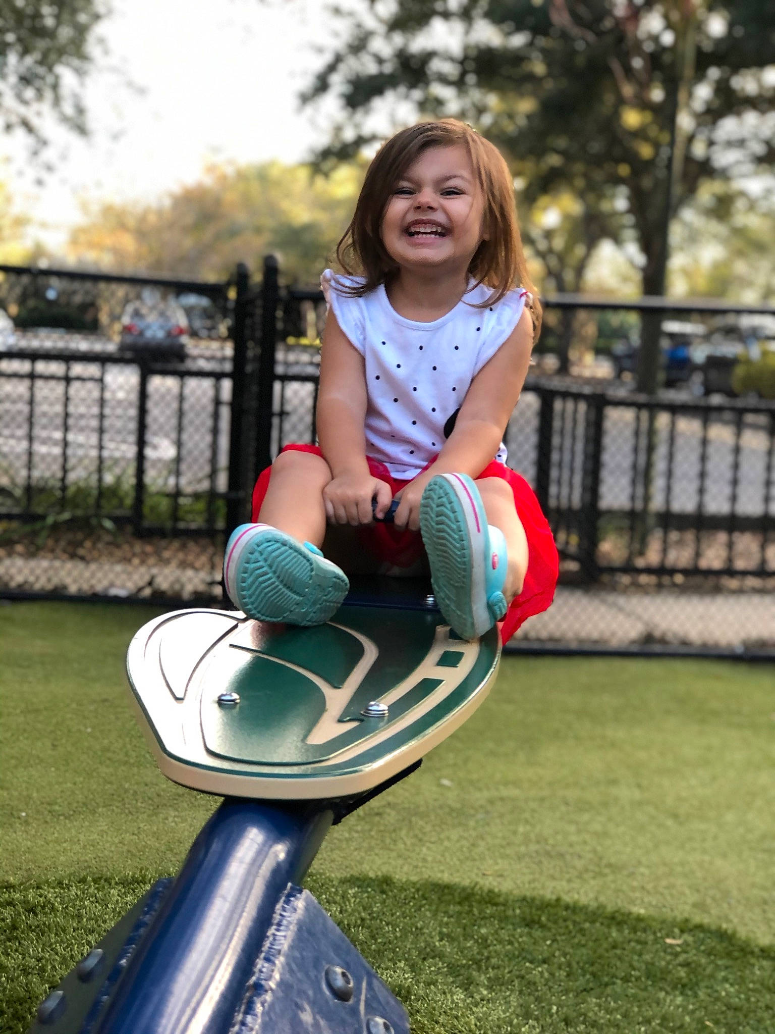Calie is registered to the contest to win money with this photo: child, electric_blue, fence, fun, grass, happy, human_leg, joy, knee, leisure, outdoor_play_equipment, person, recreation, sitting, sky, smile, sportswear, street_fashion, t_shirt, thigh
