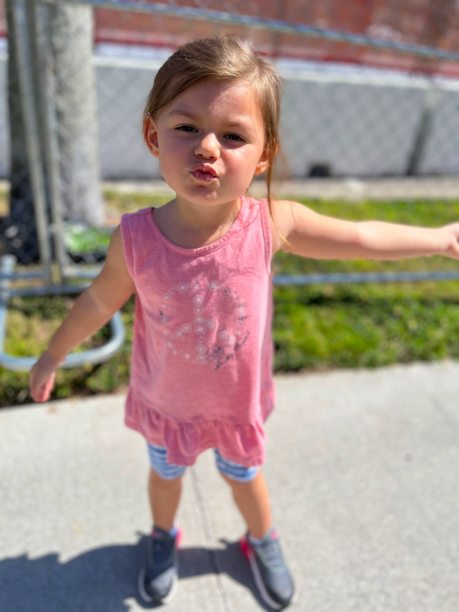 Calie is registered to the contest to win money with this photo: asphalt, face, fun, gesture, grass, happy, joint, leisure, magenta, mammal, person, pink, plant, public_space, shorts, sleeve, smile, standing, t_shirt, toddler