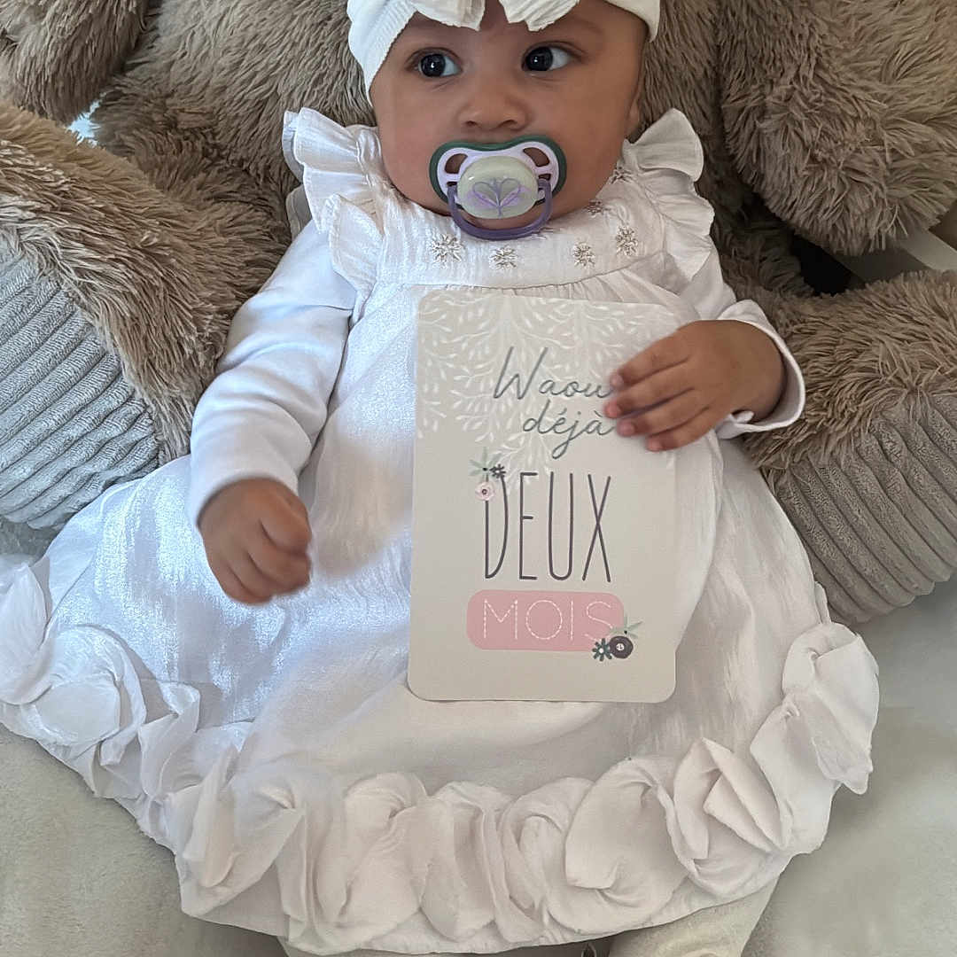 Ysalia participe au concours pour gagner de l'argent avec cette photo : baby, big_eyes, bow, closeup, cushion, floral_shoes, hand, headwrap, indoor, infant, milestone_card, pacifier, plush_toy, portrait, ruffles, sitting, soft_texture, teddy_bear, tights, white_dress