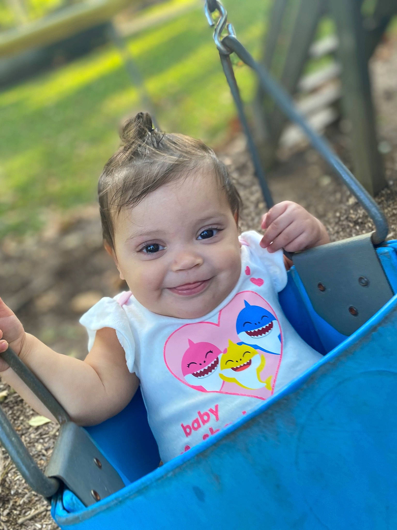 Azalea is registered to the contest to win money with this photo: baby_toddler_clothing, blue, child, eye, face, fun, grass, happy, head, human_settlement, joy, leisure, outdoor_play_equipment, outdoor_recreation, person, public_space, recreation, skin, smile, summer