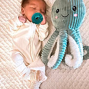 Cole joined the competition — help win amazing prizes! baby, newborn, pacifier, sleeping, plush_toy, octopus, stuffed_animal, blanket, soft_texture, cute, infant, child, cozy, white_clothing, striped_socks, bedtime, resting, smiling_toy, childhood, comfort