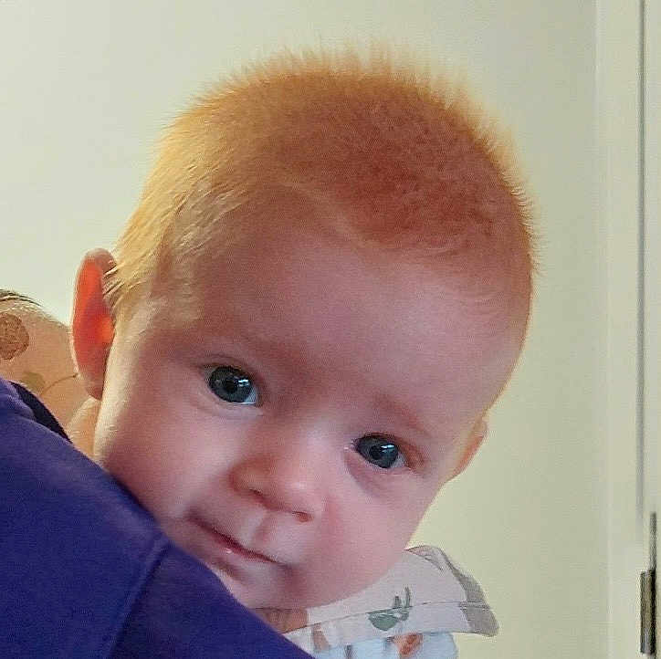 Eziah joined the competition — help win amazing prizes! baby, infant, child, face, portrait, close_up, blue_eyes, red_hair, cheeks, skin, looking_at_camera, being_held, shoulder, purple_cloth, collar, indoors, door, soft_lighting, cute, expression