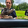 Nelson joined the competition — help win amazing prizes! woman, cat, outdoor, car, green_grass, cloudy_sky, mirror, holding, pet, fur, white_paws, gray_fur, casual_clothing, necklace, trees, residential_area, side_view_mirror, reflection, daytime, nature