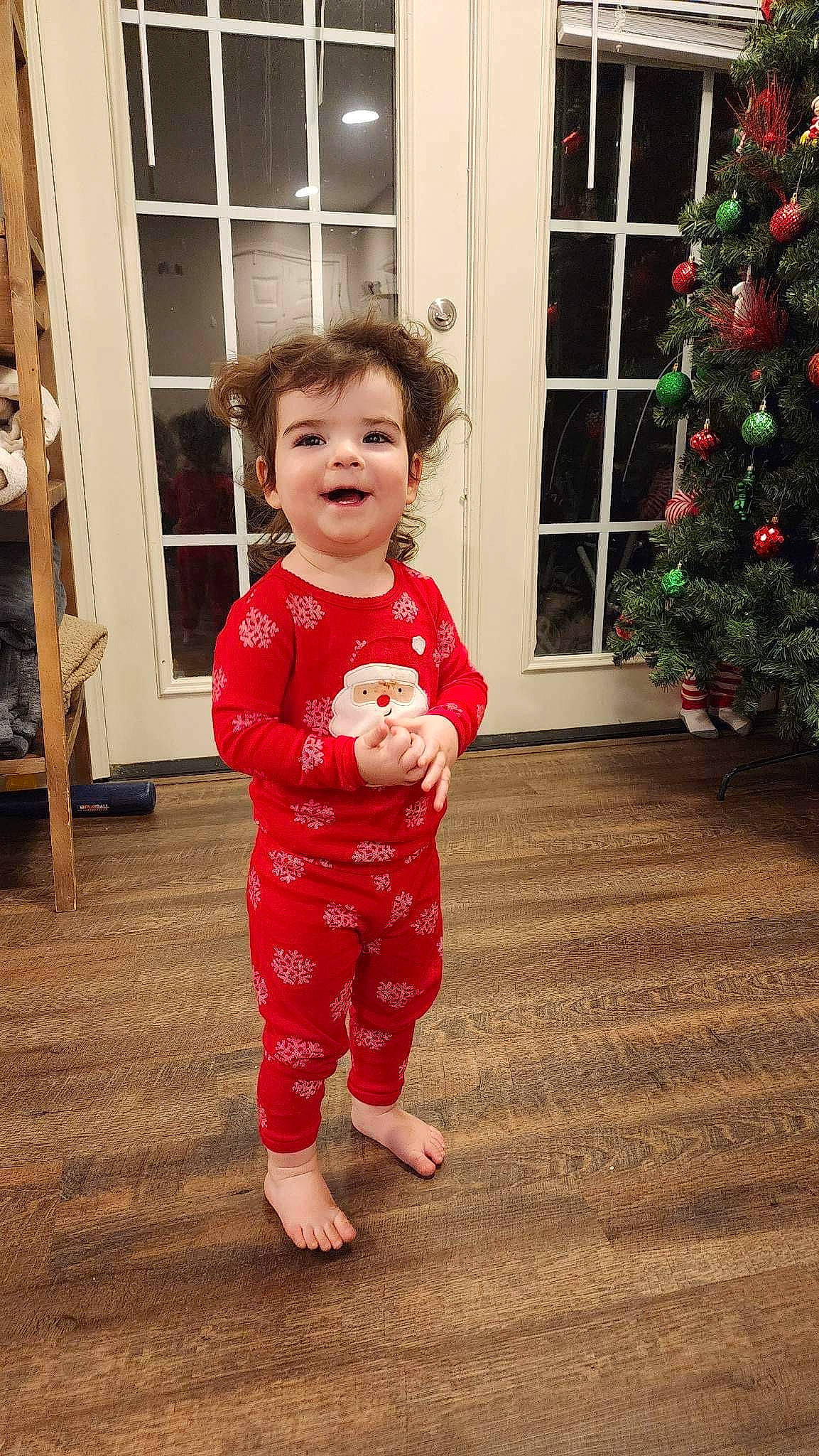 Macie is registered to the contest to win money with this photo: baby, baby_toddler_clothing, beauty, child, christmas_tree, door, dress, event, facial_expression, flooring, fun, happy, head, joy, pattern, person, sleeve, smile, standing, toddler