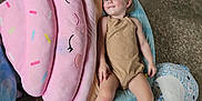 Astella is registered to the contest to win money with this photo: blanket, blue, bottle, child, clothing, concrete, cupcake, cushion, floor, indoor, leopard_print, person, pink, plush_toy, purple, relaxing, smile, sprinkles, toddler, toy