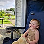 toddler, child, smiling, stuffed_animal, outdoor_chair, patio, garden, sunny_day, blue_chair, clothing, happy, face, short_hair, plush_toy, concrete_floor, house_exterior, greenery, daylight, casual, relaxed