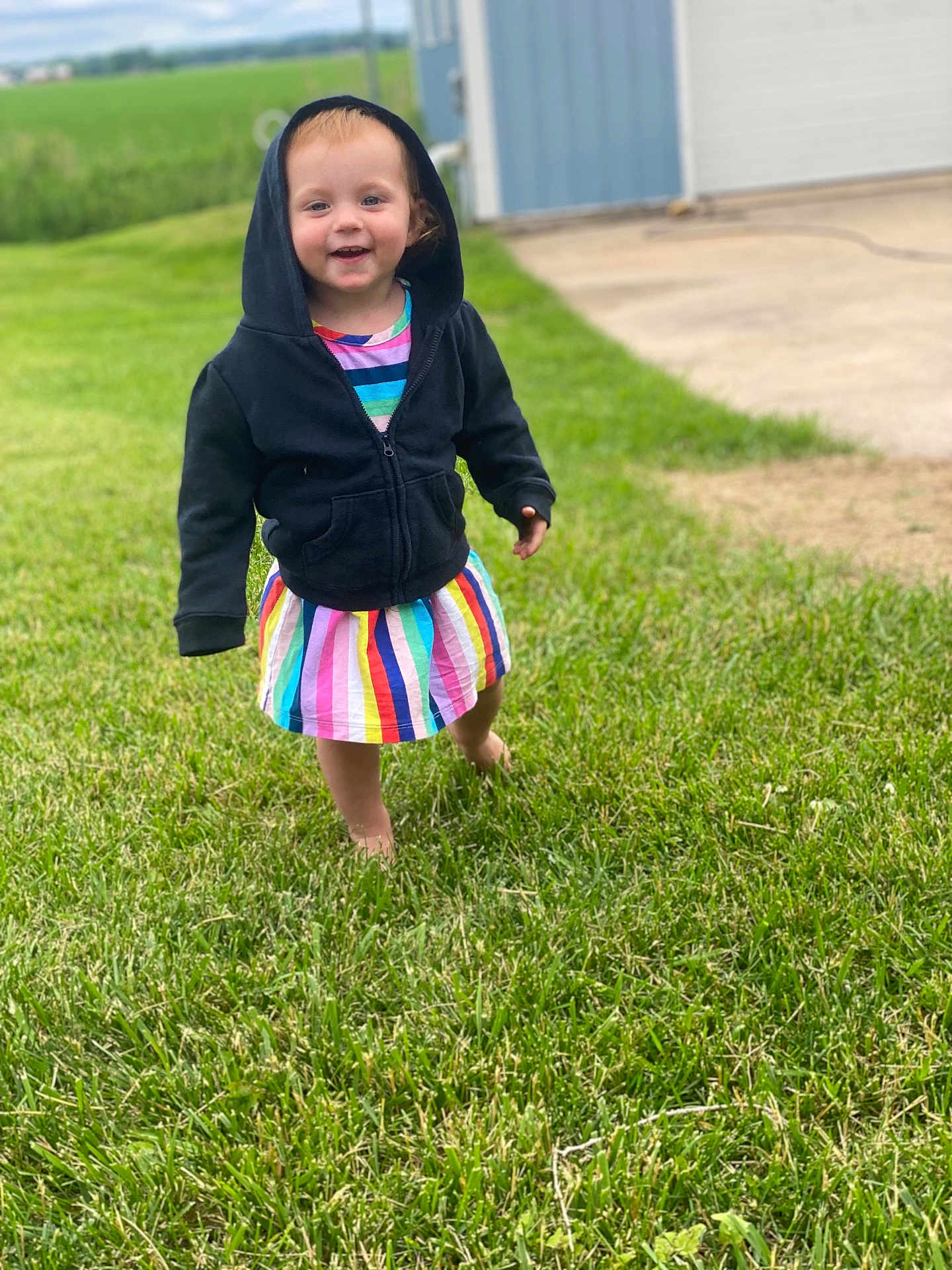 Astella joined the competition — help win amazing prizes! toddler, child, hoodie, rainbow_dress, grass, outdoor, barefoot, smiling, happy, greenery, building, shed, field, nature, portrait, walking, person, daylight, casual_clothing, young_child