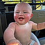 baby, child, smiling, happy, rosy_cheeks, seat, straps, outdoor, sunlight, skin, face, hand, arm, blue_eyes, bald, infant, cute, pointing, closeup, portrait