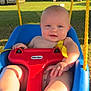 Parker is registered to the contest to win money with this photo: baby, child, swing, outdoor, grass, sunlight, playground, toys, blue, red, yellow, smiling, happy, face, legs, feet, hand, nature, tree, vehicle