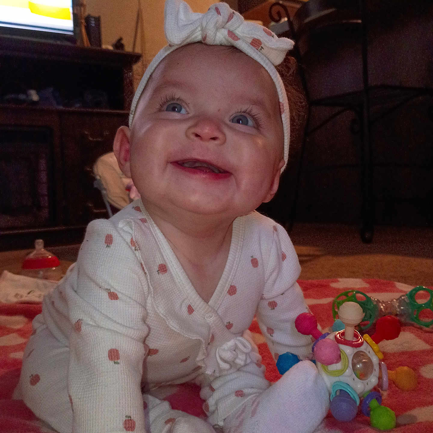 Mimikwah'Alani joined the competition — help win amazing prizes! baby, blanket, child, colorful, crawling, cute, expression, face, floor, furniture, happy, headband, indoor, infant, living_room, onesie, person, play, smiling, toy