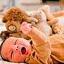baby, infant, sleepy, yawning, bed, blanket, stuffed_animal, toy, cozy, clothing, hand, face, mouth, skin, person, indoor, closeup, lying_down, soft, cute