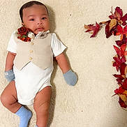 Alhadi is registered to the contest to win money with this photo: baby, infant, vest, mittens, socks, carpet, autumn_leaves, number_one, celebration, cute, portrait, child, laying_down, soft_texture, decor, fall, seasonal, smile, young_child, indoor