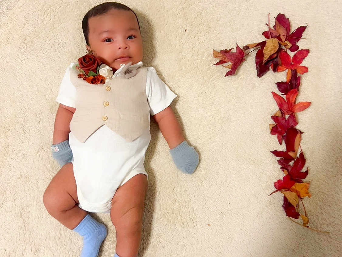 Alhadi is registered to the contest to win money with this photo: baby, infant, vest, mittens, socks, carpet, autumn_leaves, number_one, celebration, cute, portrait, child, laying_down, soft_texture, decor, fall, seasonal, smile, young_child, indoor