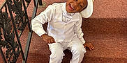 Braxton joined the competition — help win amazing prizes! child, boy, smiling, winking, white_suit, hat, stairs, carpet, black_shoes, railing, indoors, happy, formal_wear, portrait, person, fashion, cute, dressed_up, sitting, fun