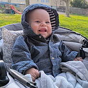 Marius participe au concours pour gagner de l'argent avec cette photo : baby, blanket, child, clothing, cold_weather, cute, face, grass, happy, hooded_jacket, infant, nature, outdoor, park, person, playground, seated, smiling, stroller, trees
