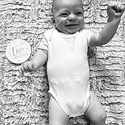 Arlo is registered to the contest to win money with this photo: baby, infant, smiling, onesie, blanket, milestone_marker, two_months, lying_down, happy, cute, portrait, monochrome, texture, arm_raised, child, young_baby, human, soft, celebration, face