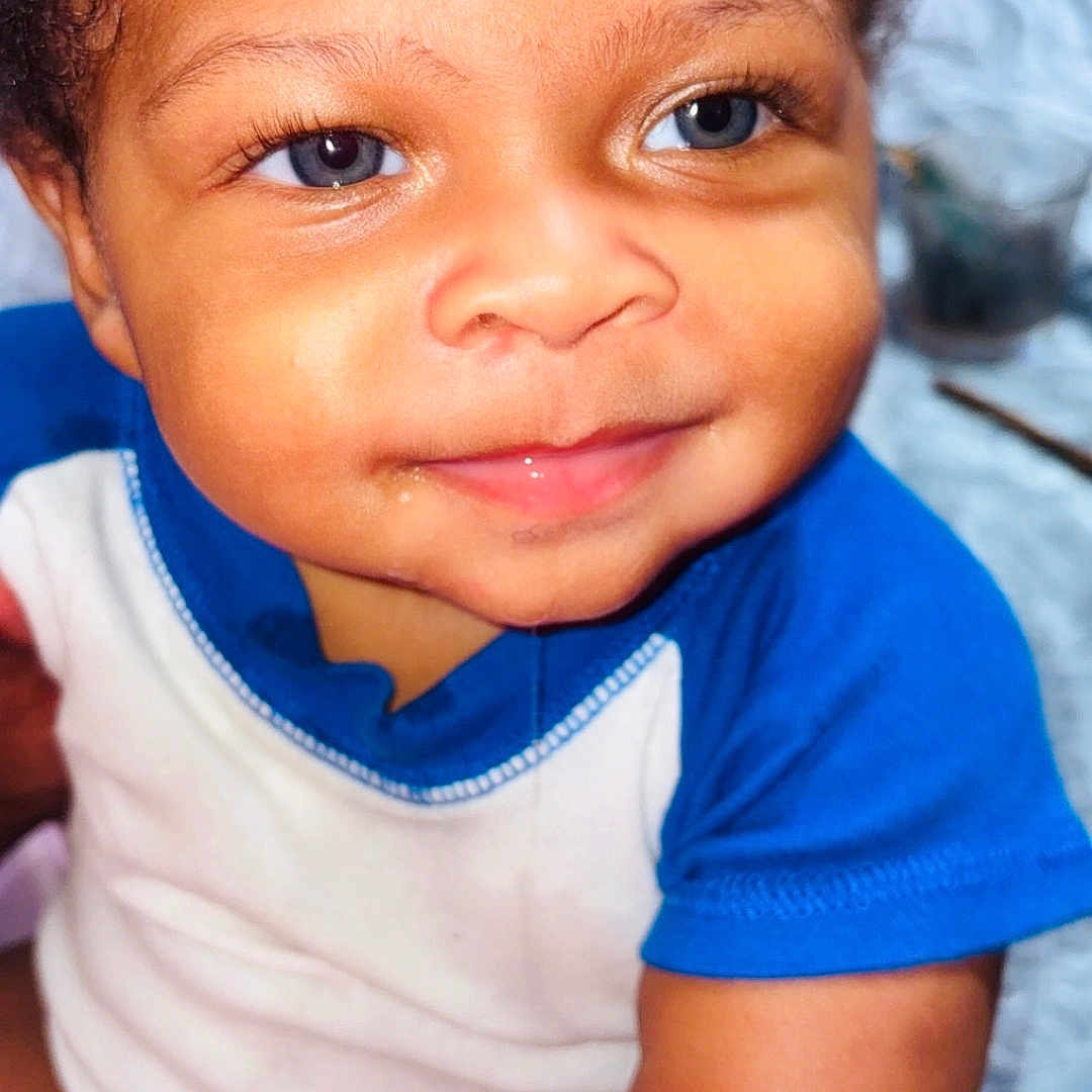 Jahkai Jean joined the competition — help win amazing prizes! arm, baby, baby_clothes, blue_eyes, child, closeup, curly_hair, cute, expression, face, happy, indoors, infant, onesie, person, portrait, skin, smiling, soft_lighting, young