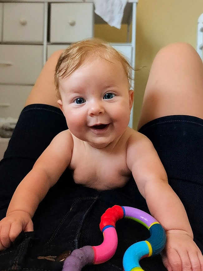 Spring is registered to the contest to win money with this photo: baby, smiling, blue_eyes, toy, indoor, person, child, happy, playful, hands, legs, clothing, face, infant, closeup, cute, skin, human, expression, joy