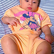 Elena is registered to the contest to win money with this photo: baby, child, infant, striped_bed_sheet, minnie_mouse, clothing, peach_color, cute, portrait, laying_down, soft_lighting, indoor, person, young_child, short_hair, expression, casual, relaxed, foot, hand