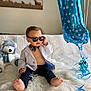 baby, child, sunglasses, blazer, bow_tie, balloon, number_one, teddy_bear, blanket, indoor, cute, fashion, portrait, smiling, feet, furniture, happy, person, decor, casual