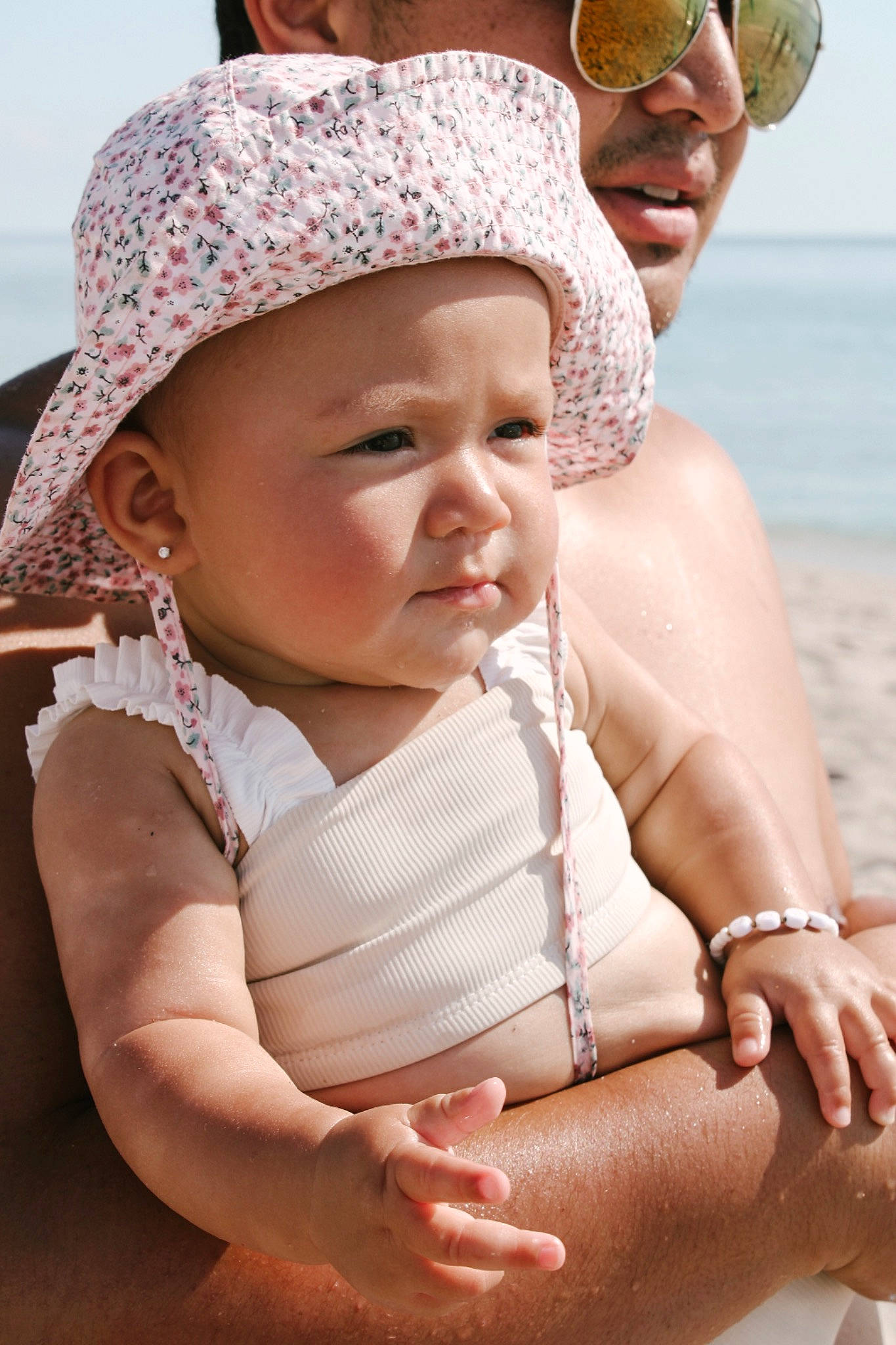 Jane is registered to the contest to win money with this photo: azure, baby, beach, cap, comfort, face, facial_expression, fun, happy, hat, headwear, human, interaction, leisure, organ, person, photograph, skin, sky, summer