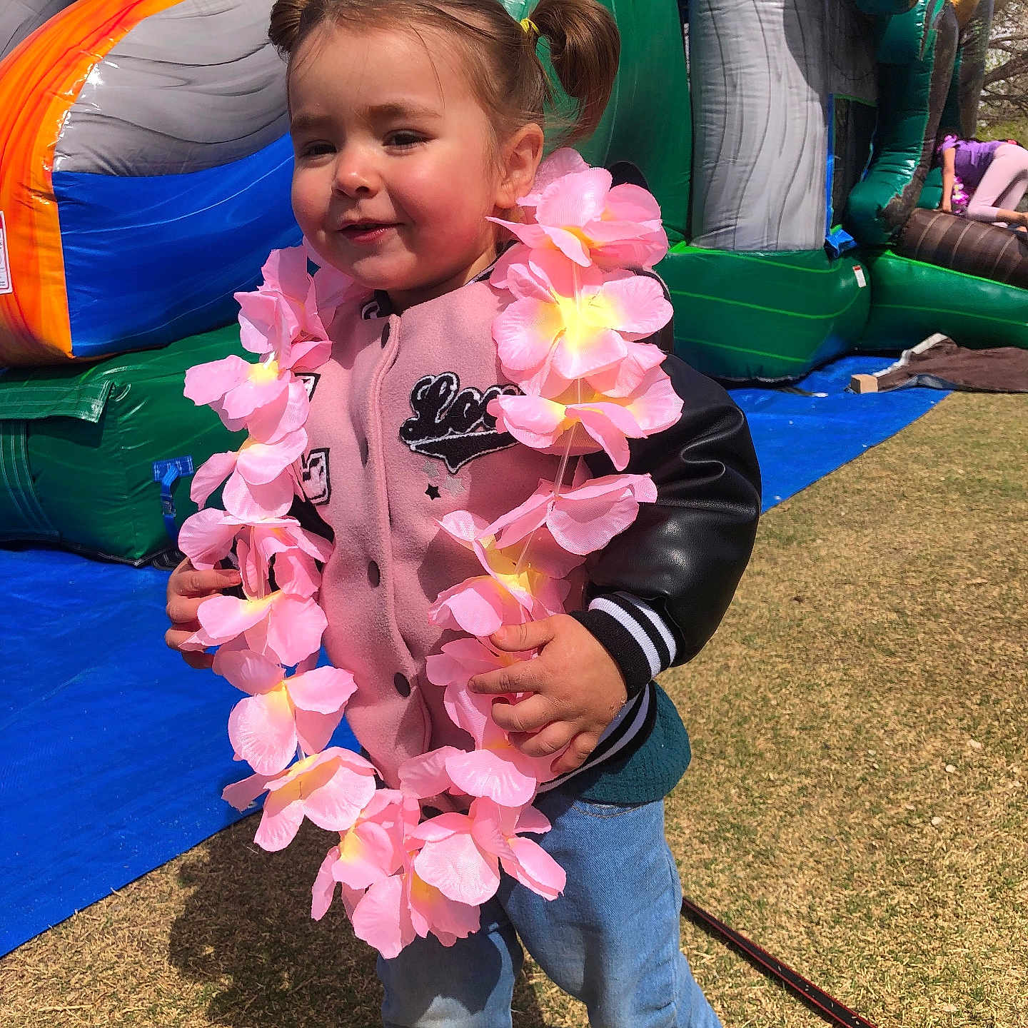 Demesia is registered to the contest to win money with this photo: child, cute, daytime, flower_lei, fun, girl, grass, happy, inflatable, jacket, jeans, leisure, outdoor, person, pigtails, pink, play, playground, smiling, sunny