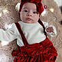 baby, infant, red_bow, red_headband, white_shirt, velvet_clothing, plush_blanket, lights, flower_decor, cute, portrait, indoor, child, young_baby, face, looking_at_camera, soft_texture, cozy, holiday_outfit, adorable