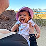 Janelle joined the competition — help win amazing prizes! baby, child, smiling, hat, pink_hat, outdoor, sunny, rocky_landscape, adult_hand, blue_sky, water, nature, laughing, happy, person, holding, short_sleeve, infant, scenic, daylight