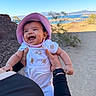Janelle joined the competition — help win amazing prizes! baby, child, smiling, laughing, hat, pink_hat, teddy_bear_print, white_clothing, hands, desert, outdoor, sunny, blue_sky, nature, person, holding, happy, portrait, infant, scenery
