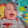 Colter is registered to the contest to win money with this photo: baby, smiling, child, play_mat, colorful, hand, clothing, short_sleeve, indoor, happy, portrait, infant, face, tongue_out, person, cute, toy, pattern, baby_girl, baby_boy