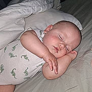 Colter joined the competition — help win amazing prizes! baby, sleeping, onesie, dinosaur_print, bed, pillow, blanket, infant, peaceful, resting, cute, child, soft_lighting, indoors, portrait, closeup, skin, hand, head, face