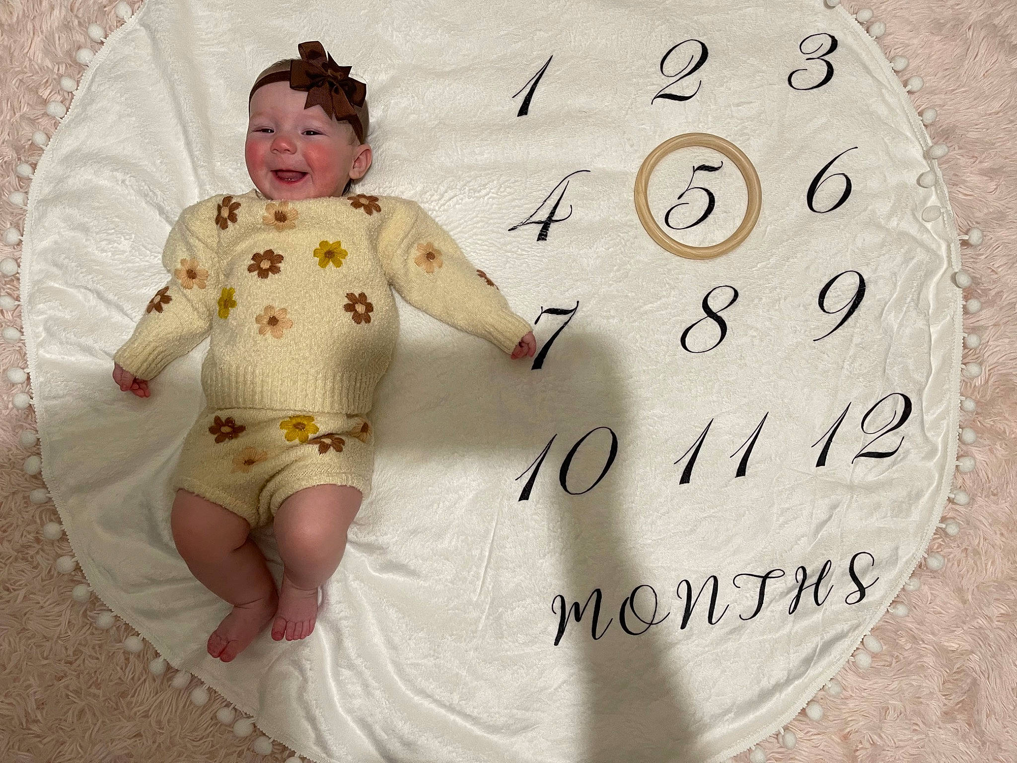 Remington is registered to the contest to win money with this photo: baby, baby_products, baby_toddler_clothing, child, circle, clock, font, happy, home_accessories, interior_design, linens, number, pattern, person, personal_protective_equipment, sitting, sleeve, smile, t_shirt, toddler