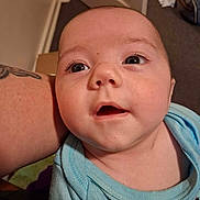 Elias joined the competition — help win amazing prizes! arm, baby, backpack, blue_clothing, carpet, child, closeup, door, expression_curious, eyelashes, eyes, face, holding, indoor, infant, mouth_open, onesie, portrait, skin, tattoo