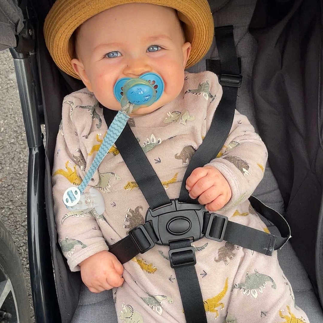 Ayden a rejoint le concours — aidez-le/la à gagner de superbes lots ! baby, blue_eyes, child, clothing, cute, dinosaur_print, face, hand, hat, infant, onesie, outdoor, pacifier, safety_harness, seat, smile, straps, stroller, wheel, young_child