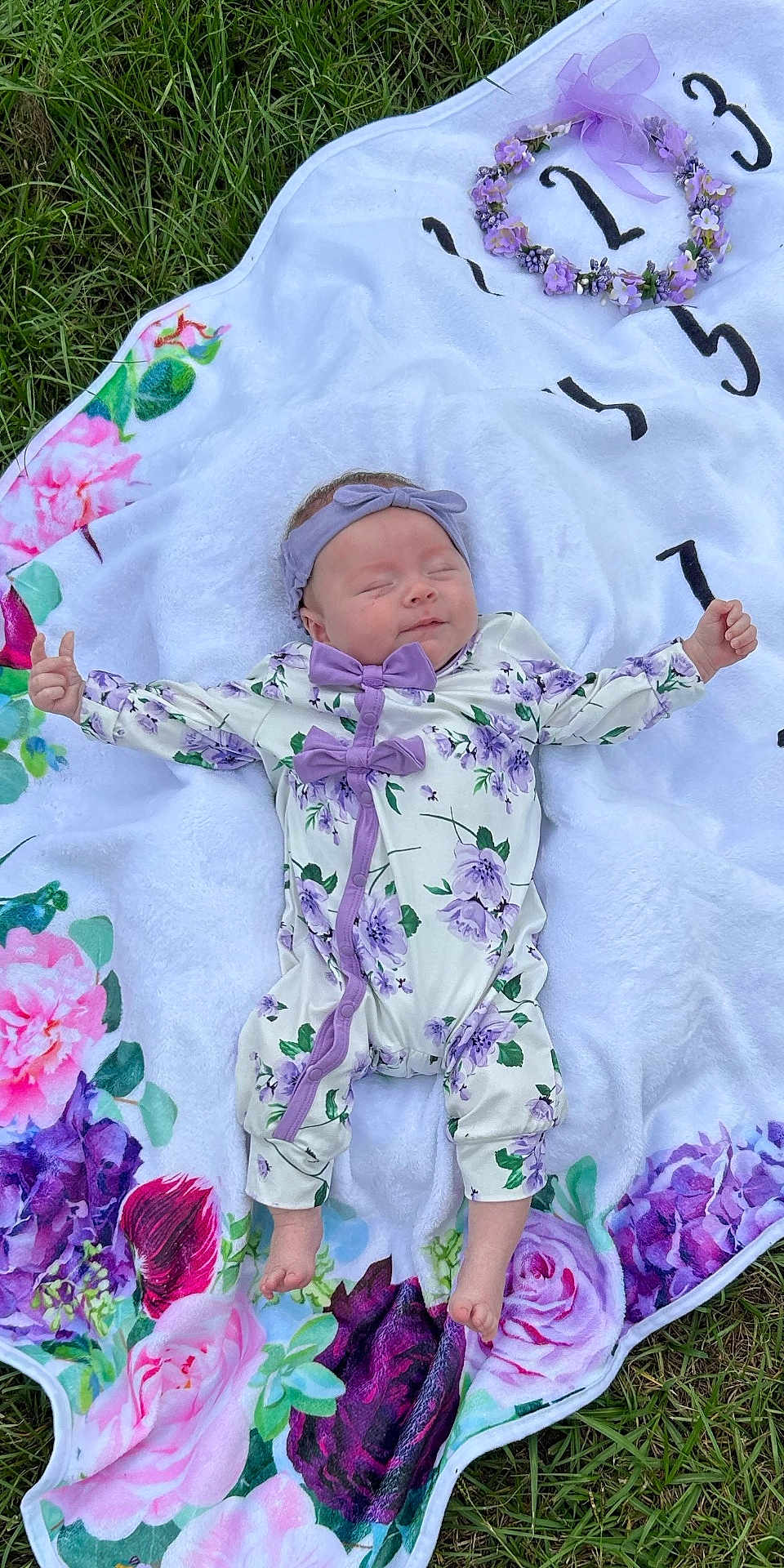 Cyndianna is registered to the contest to win money with this photo: baby, blanket, colorful, cute, floral, flower_pattern, grass, headband, infant, lying_down, nature, newborn, onesie, outdoor, peaceful, person, portrait, purple_bows, sleeping, soft_texture