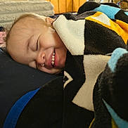 Noah is registered to the contest to win money with this photo: baby, toddler, child, smile, tooth, blanket, star_pattern, pillow, bed, cozy, sleeping, happy, face, cheek, ear, closeup, portrait, indoors, textile, nap