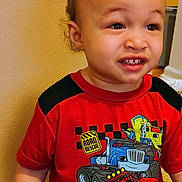 Noah joined the competition — help win amazing prizes! toddler, child, curly_hair, red_tshirt, monster_truck_graphic, toy_car, indoor, wooden_floor, beige_wall, sitting, casual_clothing, cute, young_child, expression, person, head, face, smile, short_sleeves, play