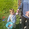 Greyson is registered to the contest to win money with this photo: adult, boy, bucket, casual_clothing, child, curious, daylight, grass, greenery, hand_holding, holding, outdoor, pants, person, play, shirt, shoes, sidewalk, stairs, sunlight