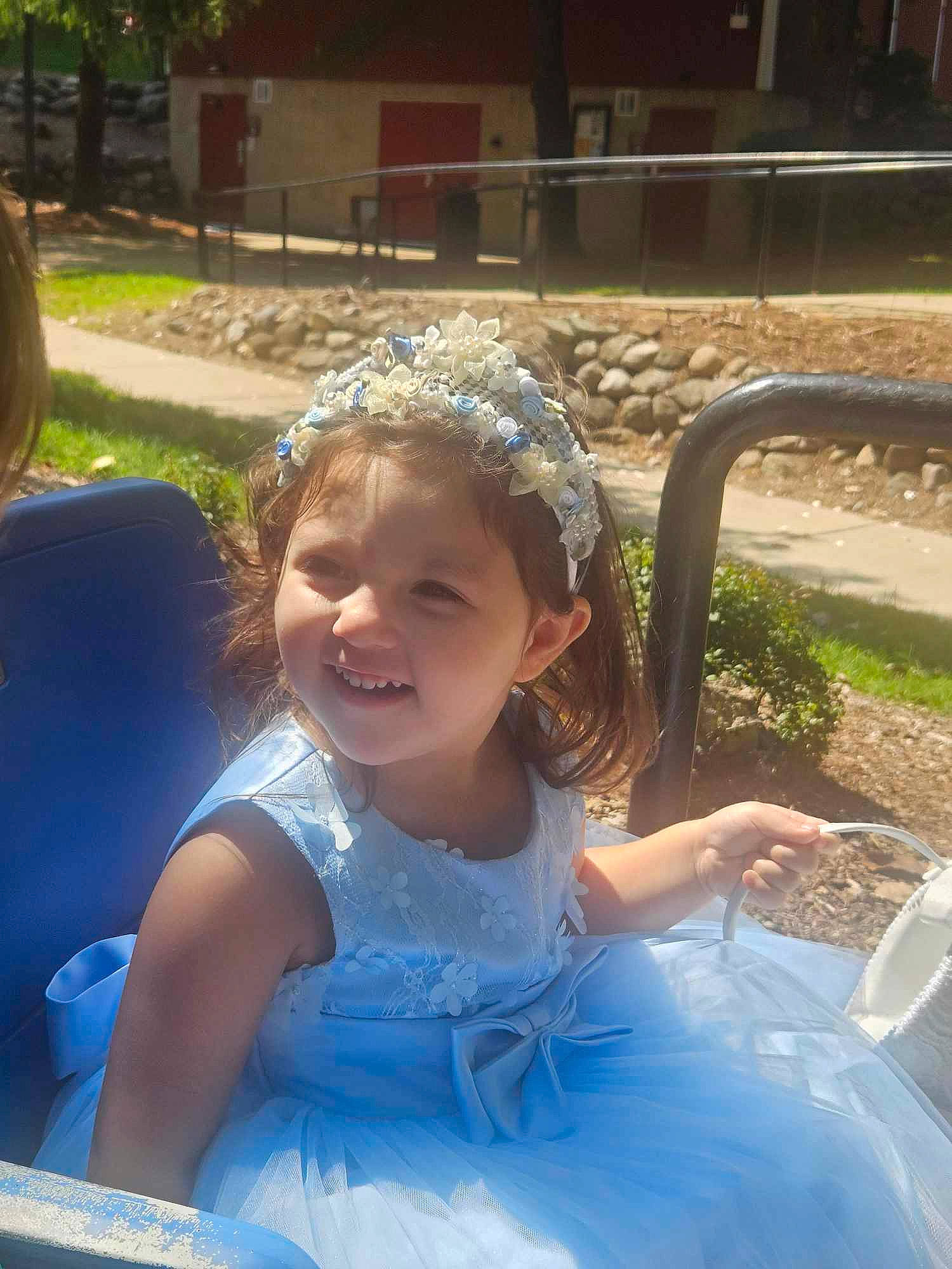 Katianna is registered to the contest to win money with this photo: chair, child, dress, event, eye, facial_expression, fun, grass, hairstyle, happy, headpiece, joy, leisure, person, plant, recreation, sitting, smile, summer, toddler