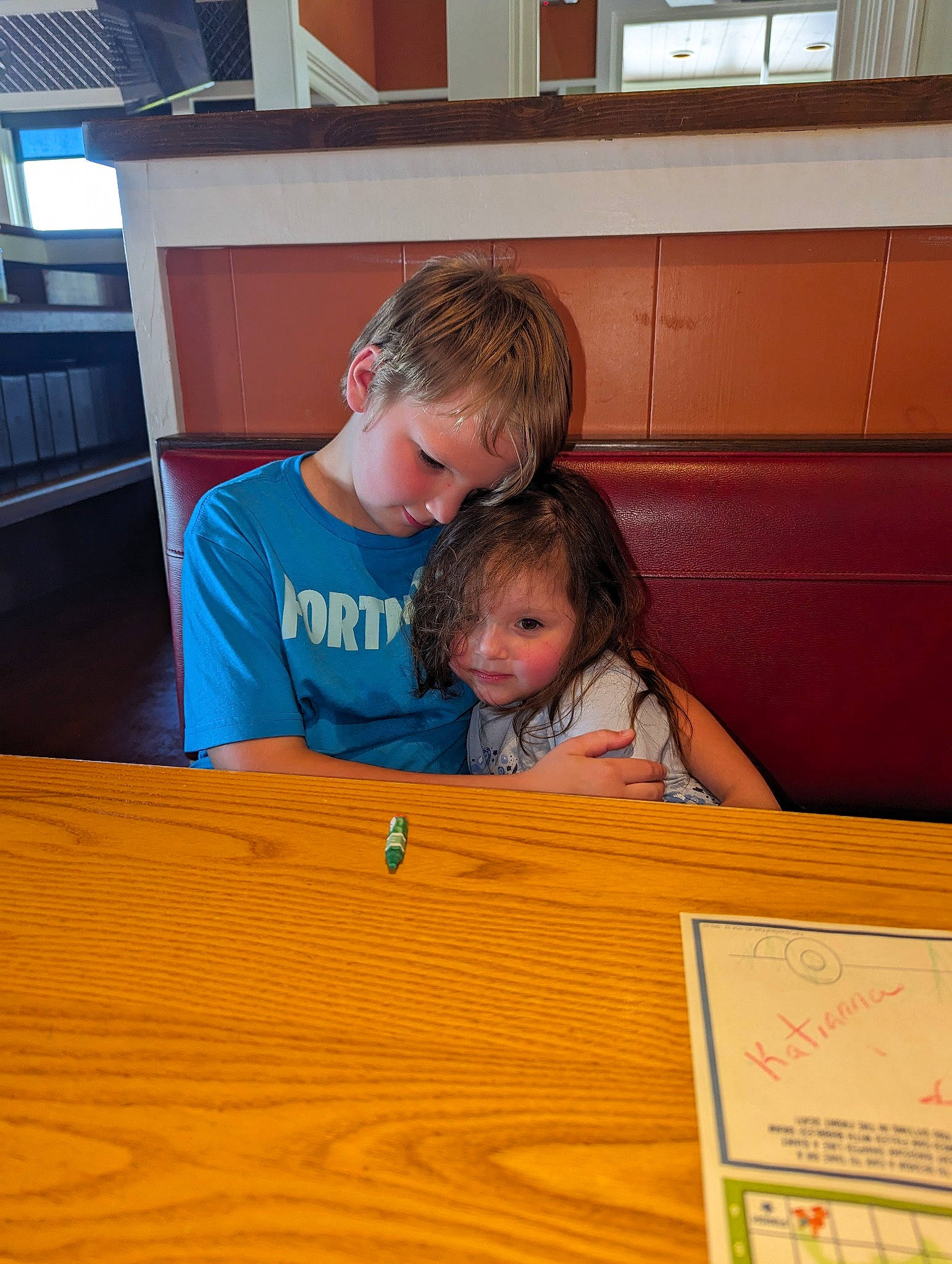 Dominic is registered to the contest to win money with this photo: bookcase, chair, child, desk, flooring, fun, happy, hardwood, leisure, person, plywood, room, shelf, sitting, smile, t_shirt, table, toddler, varnish, wood