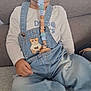 toddler, child, pacifier, denim_overalls, curly_hair, sitting, couch, indoors, cute, clothing, face, blue_eyes, patch, hand, car_socks, happy, baby, comfort, smile, young_child